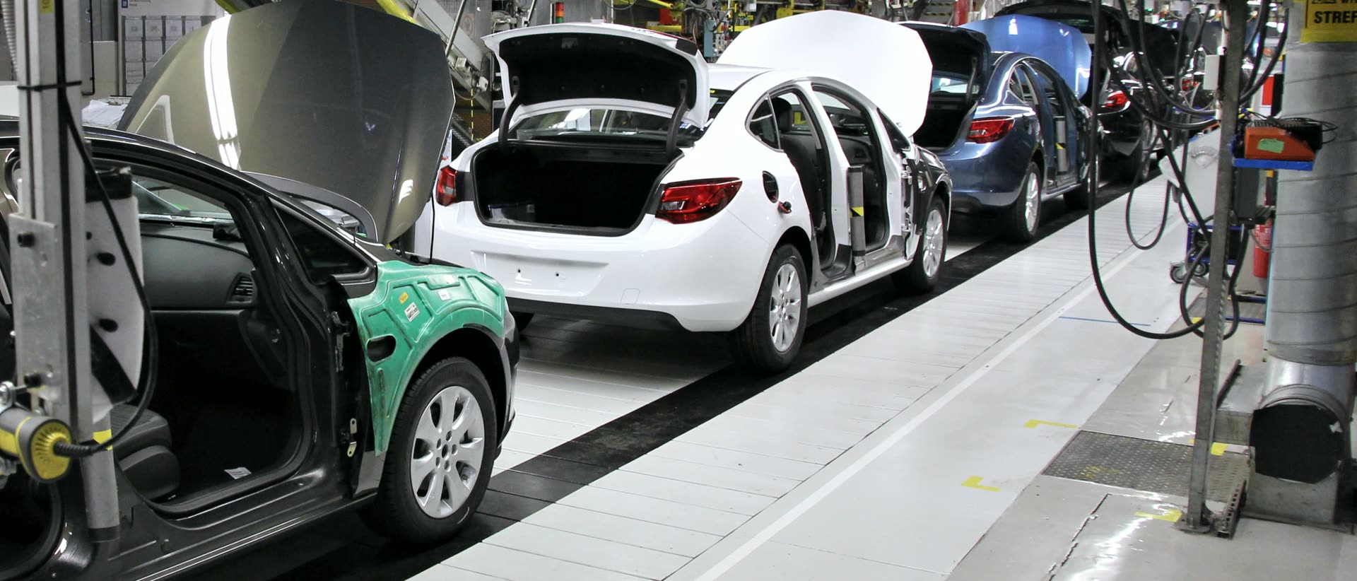 Línea de montaje automotriz: carrocerías en proceso sobre la banda, con puertas y cofre abiertos, en la nave de ensamble final